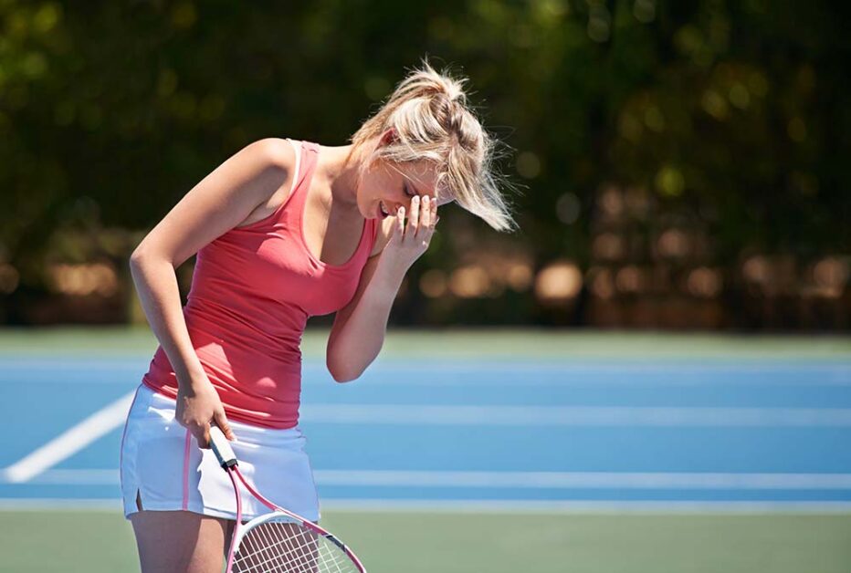 Tennis player resting on court showing signs of burnout.