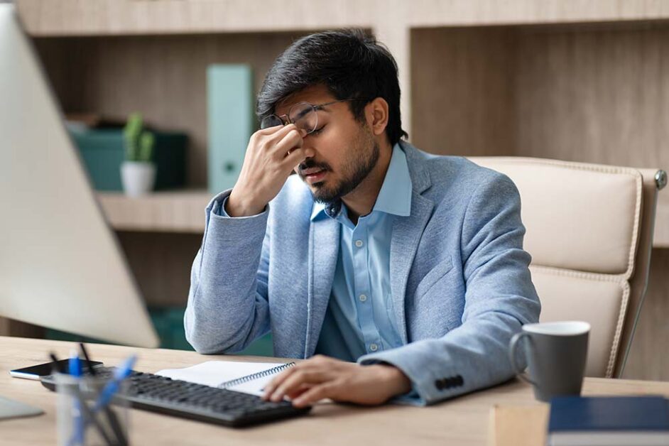Stressed Indian employee experiencing workplace burnout and emotional exhaustion at office.
