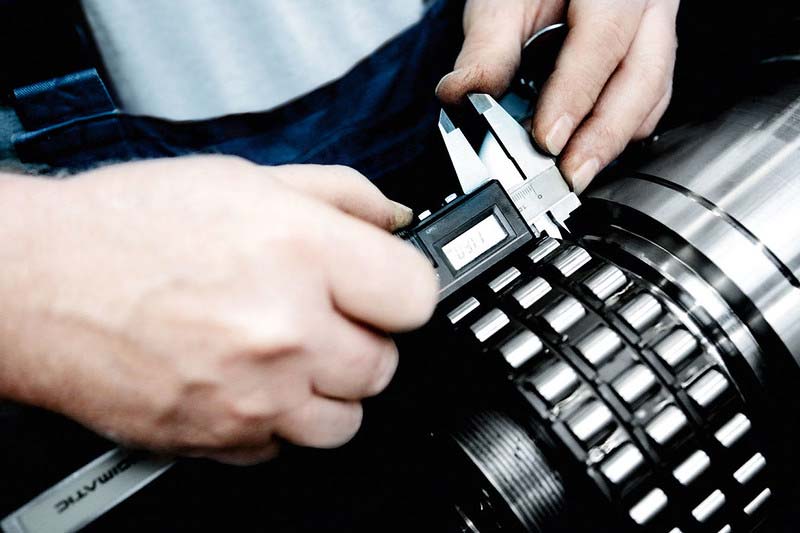 Engineer measuring press component during newspaper modernization asset assessment