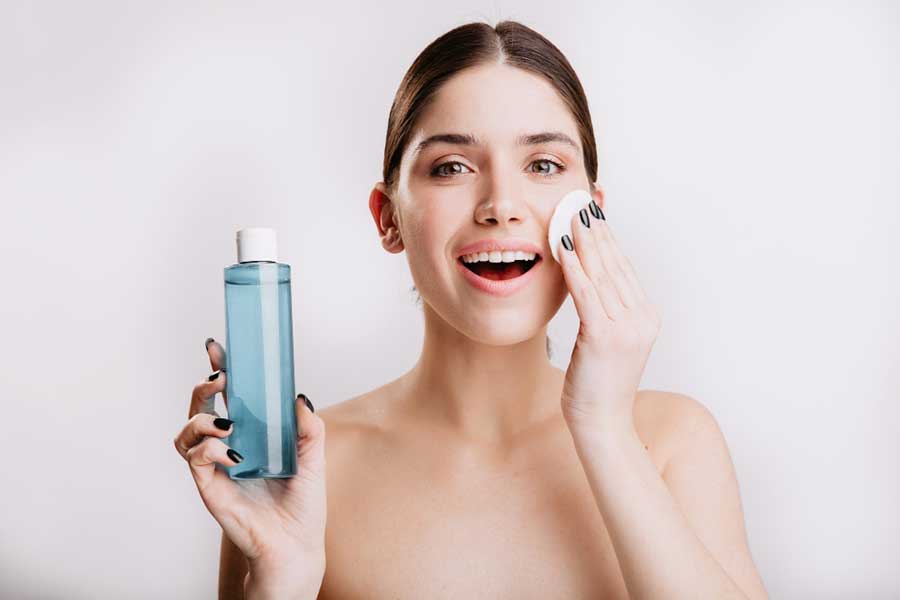 Lady using skin toner on face.