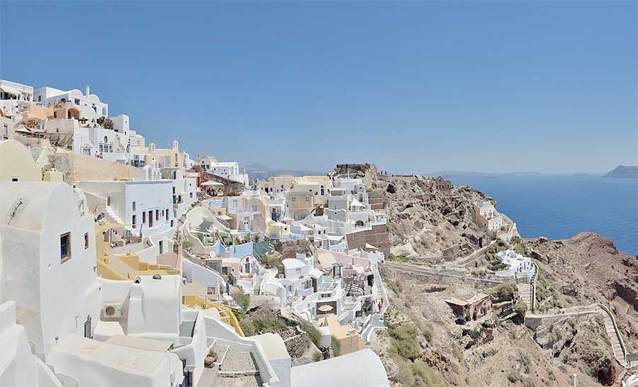 Romantic Santorini village with Byzantine castle ruins in the background.
