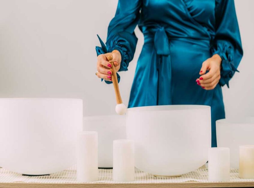  Person playing a crystal singing bowl for sound therapy.