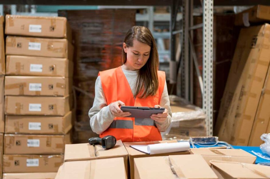 Worker managing inventory in a warehouse using a digital tablet