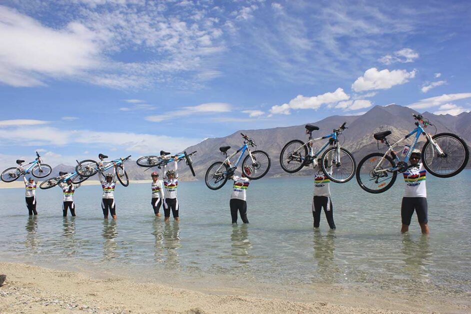 Cyclists celebrating at Pangong Tso during Southeast Ladakh expedition.