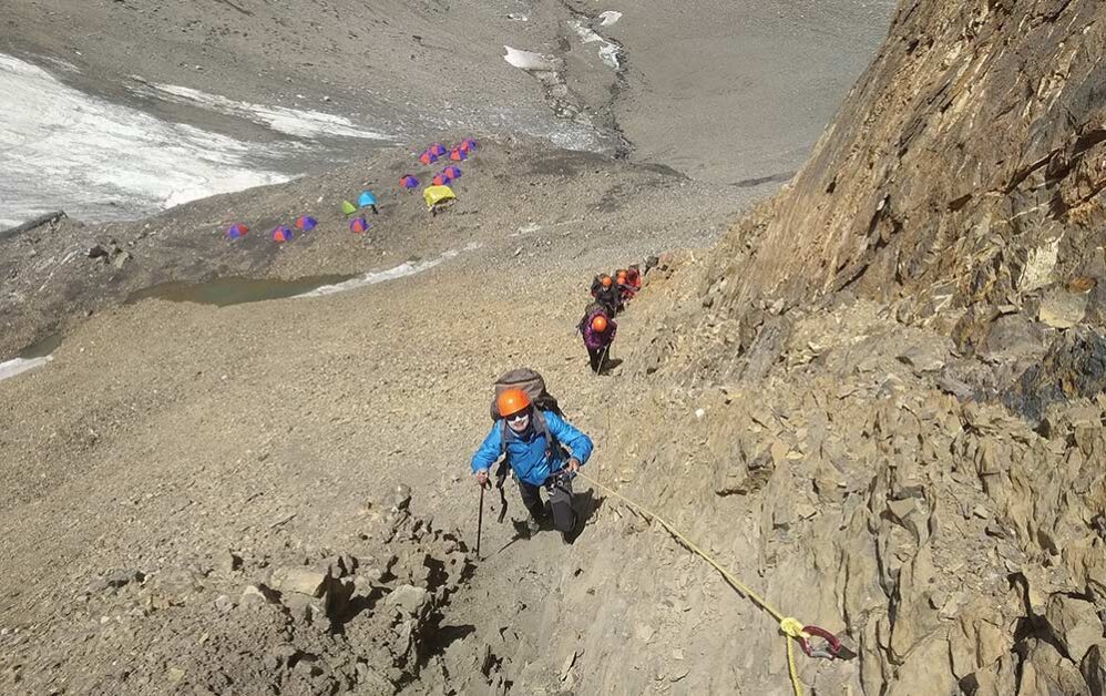 Bhavana ascending rocky slopes towards a high-altitude base camp.