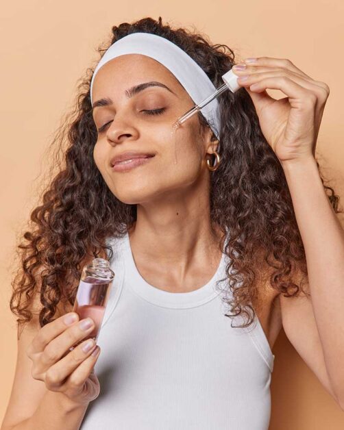 Woman applying anti-aging serum for glowing, firm, and smooth skin.