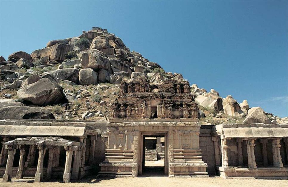 Historic Vijayanagara ruins in Hampi with rocky landscape and temple gateway.