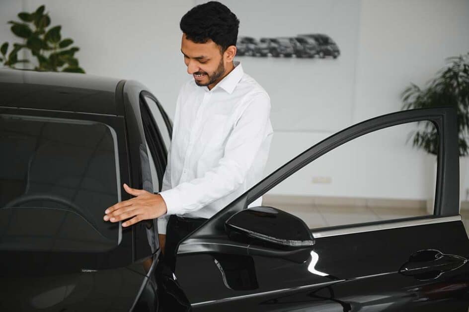 Smiling customer inspecting car after premium detailing in Chicago