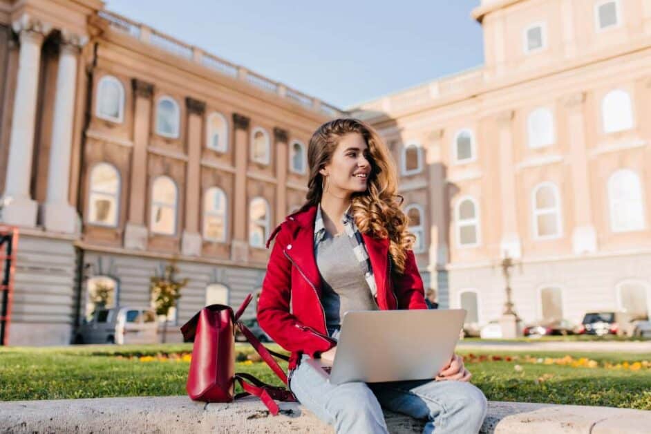 Female student with laptop studying on international university campus
