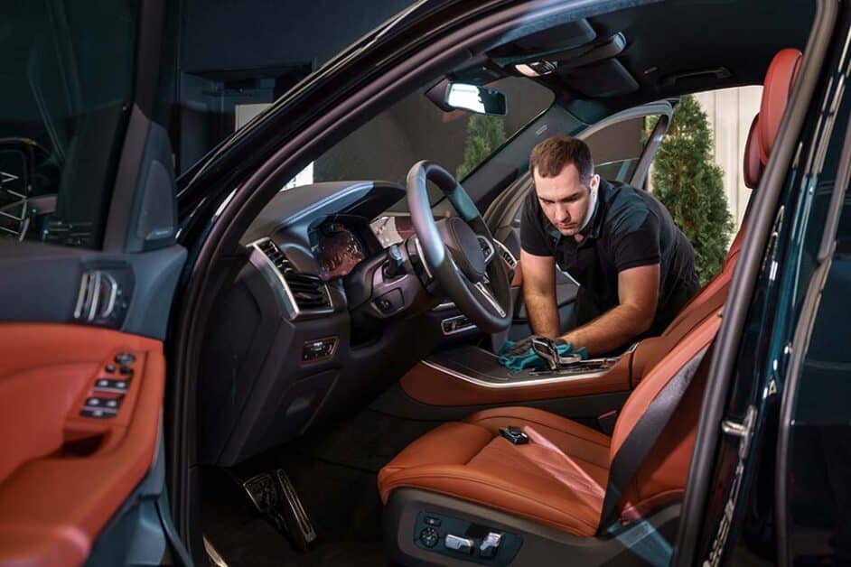 Technician performing detailed interior cleaning of luxury car Chicago
