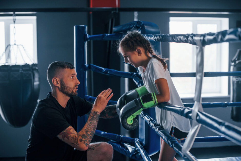 Coach guiding young boxer to build resilience and balance.