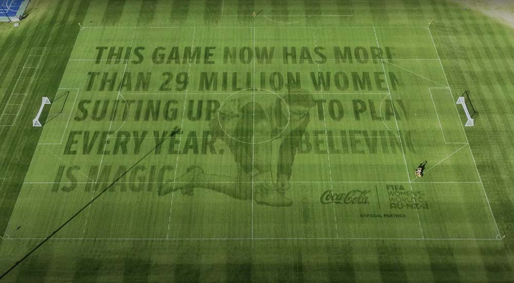 A Coca-Cola campaign message on a football field highlighting 29 million women playing yearly