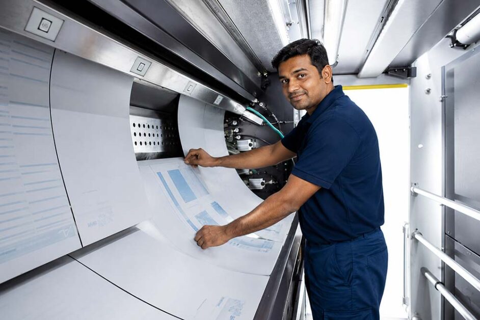 Indian print operator monitoring printed sheets before finishing workflow begins efficiently